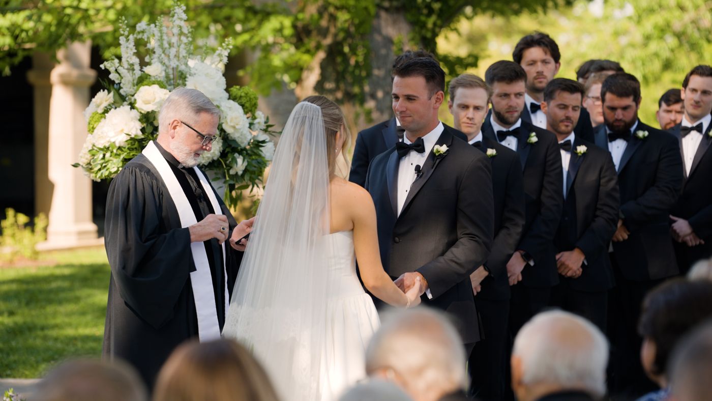 Close angle on the groom during the vows, groomsmen behind him